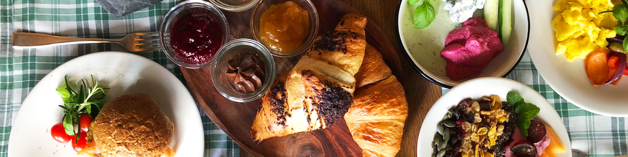 Frühstückstisch mit Croissants, Marmelade, Gemüse.