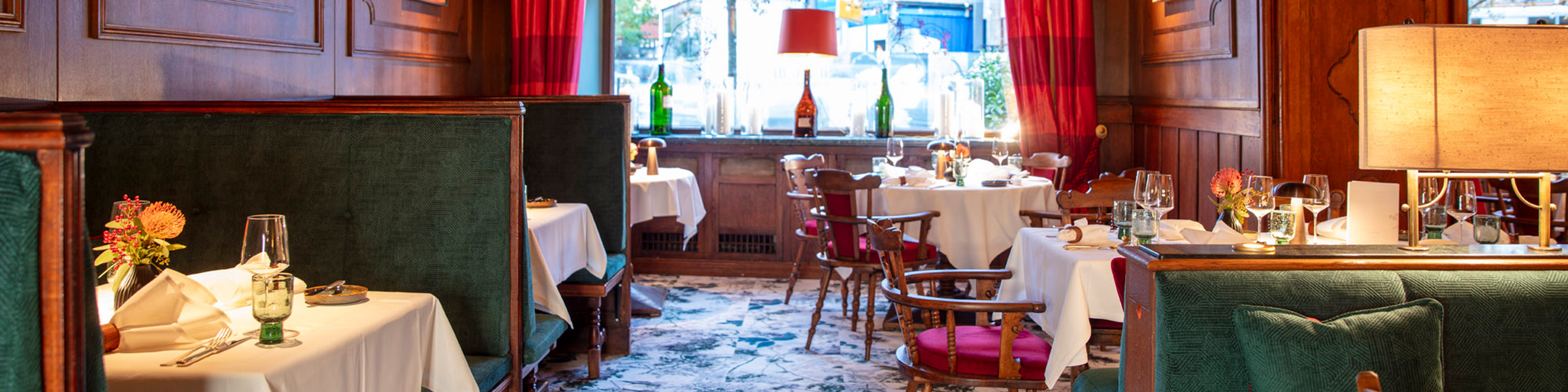 Restaurant Speiseraum mit roten Vorhängen, Stühlen und grünen Sitzbänken.