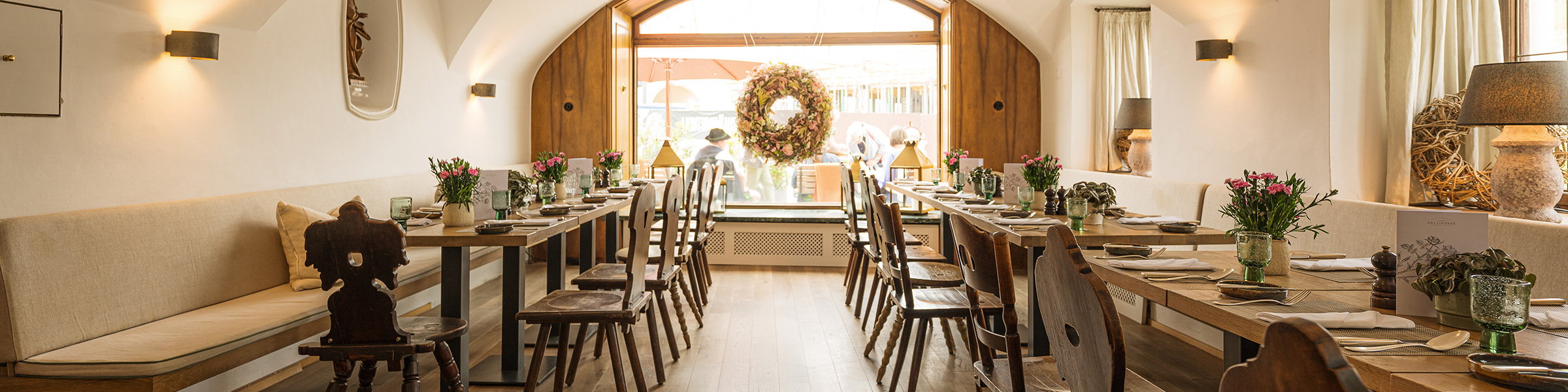 Helles natürliches Restaurant mit langen gedeckten Holztischen und Stühlen.