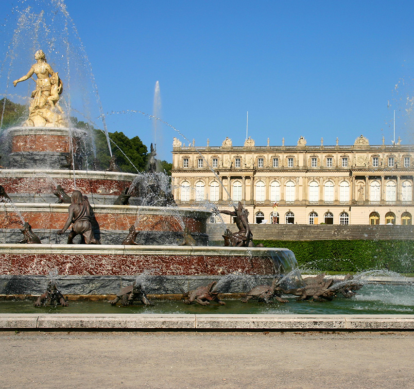 Prunkvolles Schloss mit Wassergraben und symmetrischem Garten am Herrenchiemsee.