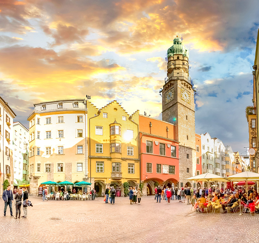 Marktplatz in der Innenstadt von Innsbruck mit Kirchenturm bei Sonnenuntergang.