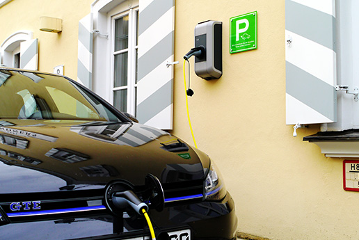 Elektroauto lädt an Ladesäule mit grünem Parkschild.