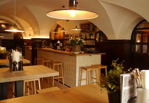 Modernes Restaurant mit Holzstühlen und heller Beleuchtung und kleiner Theke.
