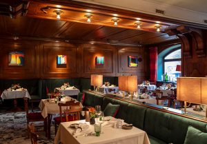 Gemütliches rustikales Restaurant mit gedeckten Tischen und beleuchteter Holzdecke.