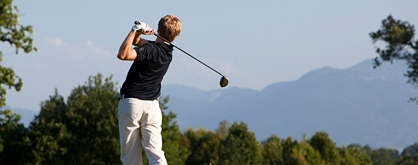 Lindners_Golf Mann beim Golfen mit Blick auf Berge im Hintergrund.