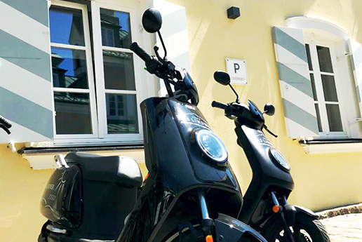 Elektroroller geparkt auf Hotelgelände mit Helm.