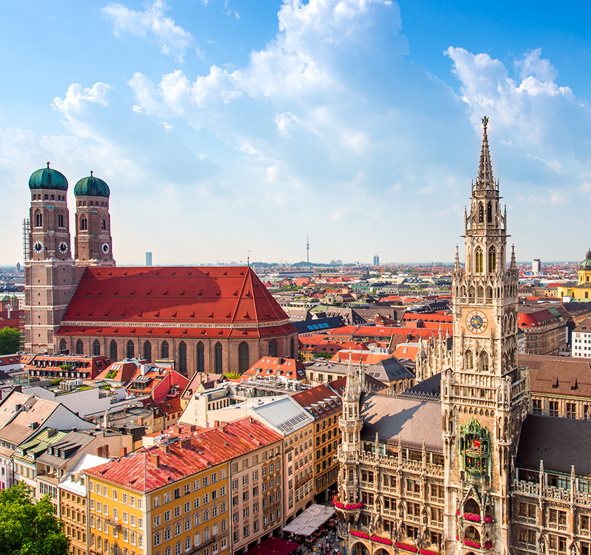 Blick über Münchner Innenstadt mit Frauenkirche bei Sonnenschein.
