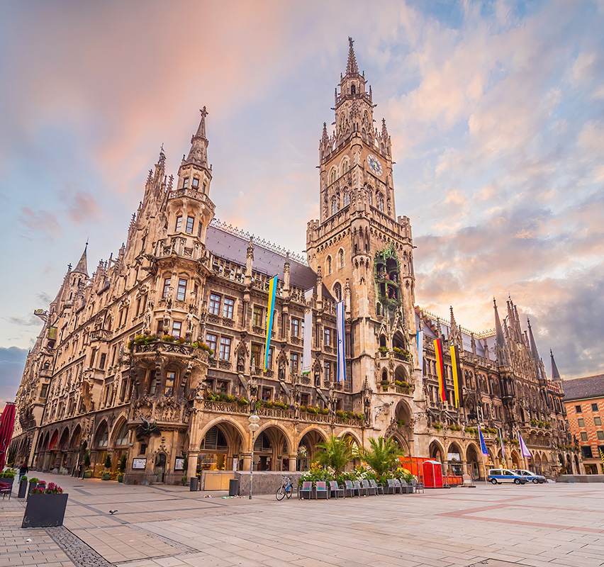 Neues Rathaus in München bei Sonnenuntergang mit Menschen davor.
