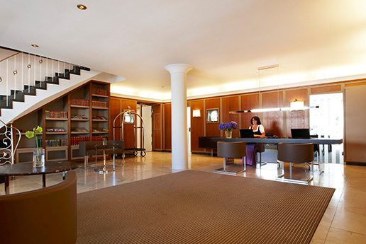 Hotelrezeption mit großem Eingangsbereich und Dame am Empfang.