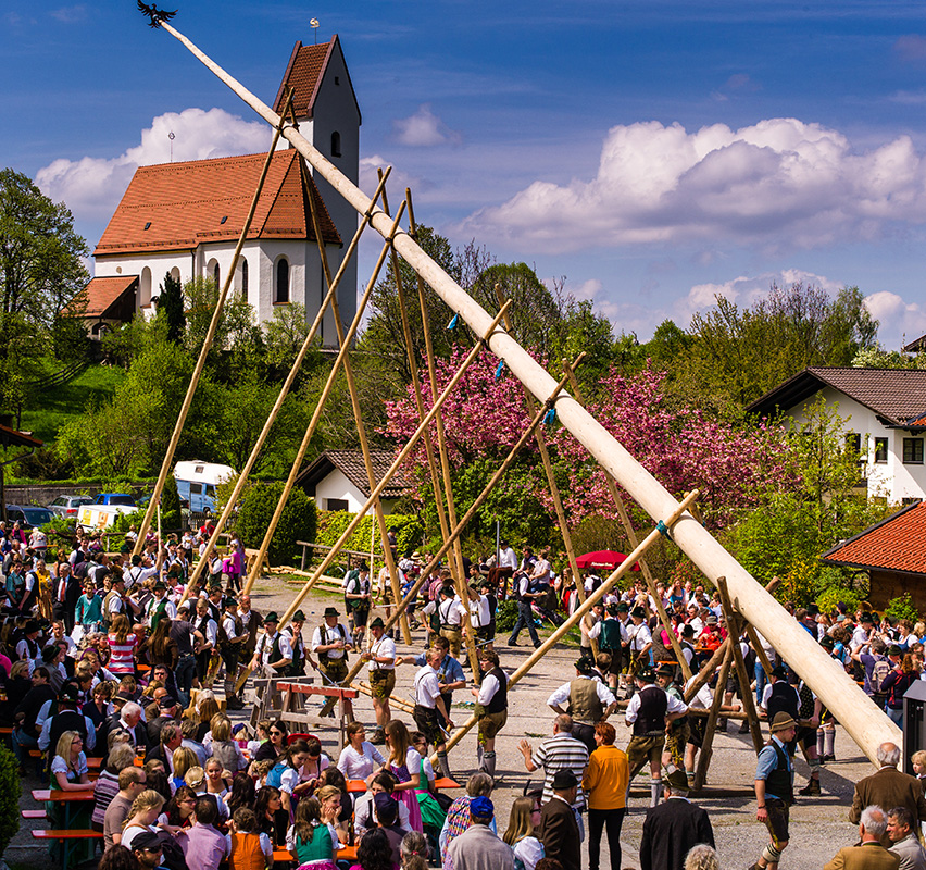 Menschenmenge bei traditionellem bayerischem Fest mit Maibaum.