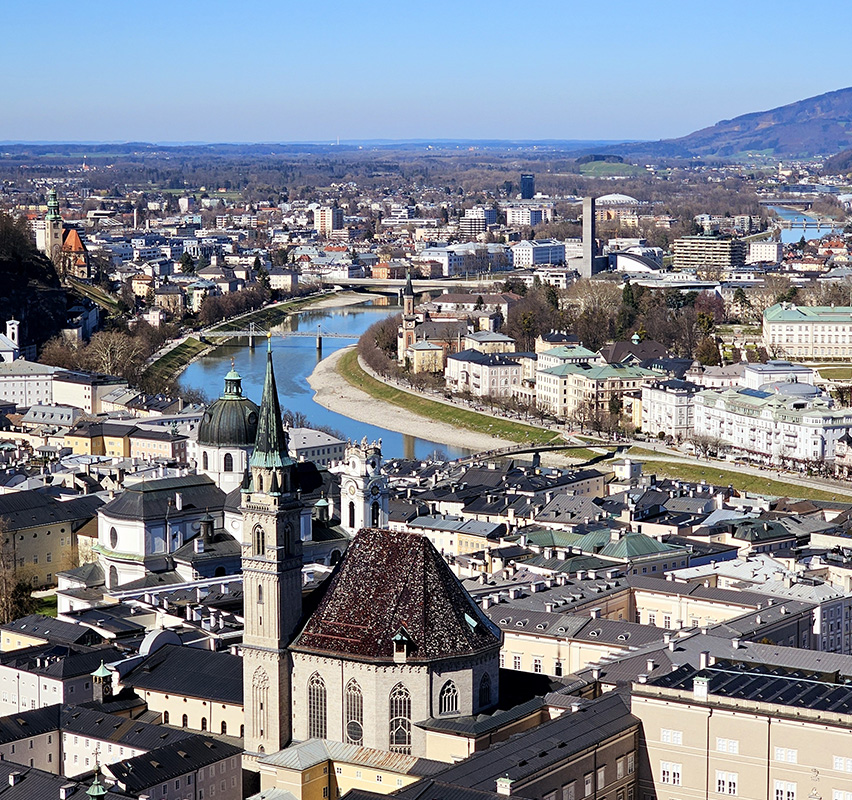 Ausblick auf Salzburg mit Kirche im Vordergrund und Fluss im Hintergrund.