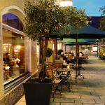 Außenbereich des Lindners Restaurants mit Tischen und Beleuchtung.