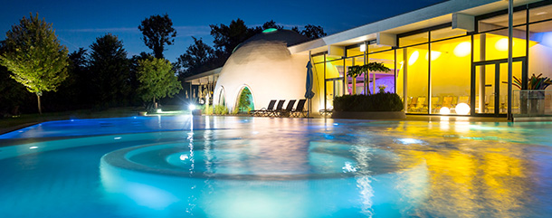 Therme_BadAibling Hotel-Spa mit Pool, Palmen und nächtlicher Beleuchtung.