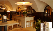 Gemütliches Restaurant mit Holztischen und Stühlen und kleiner Bar im Hintergrund.