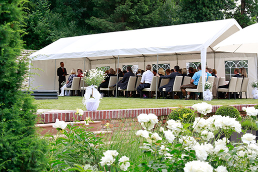 Outdoor-Veranstaltung mit weißen Zelten in einem Garten.