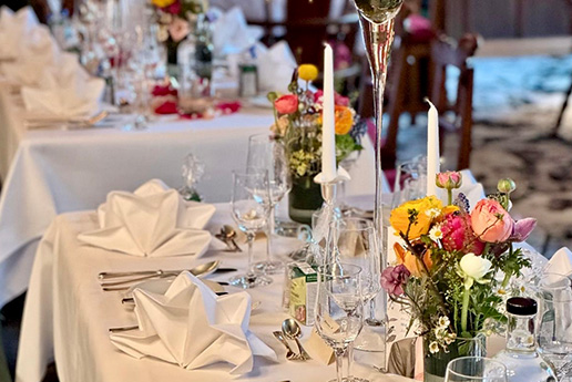 Festlich gedeckter Tisch mit weißen Servietten und Blumenschmuck.