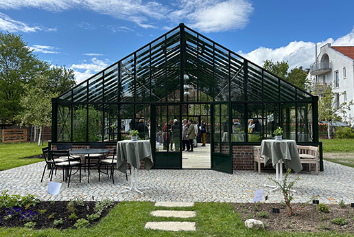 Großes modernes Glashaus in ländlicher Umgebung.