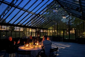 Glasüberdachter Innenhof mit gedeckten Tischen bei Nacht.