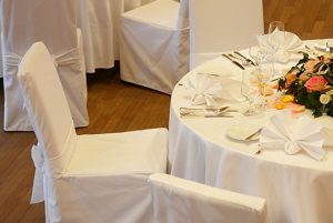 Festlich eingedeckter Hochzeitstisch mit weißen Hussen und Kerzen.