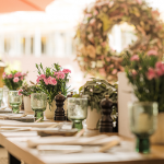 Florale Dekoration am Tisch mit rosa Blumen in einem Glasgefäß.