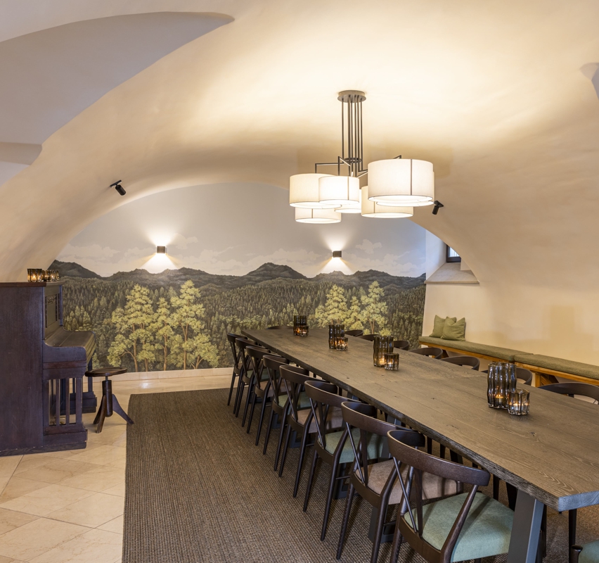 Schlosskeller - Tagungsraum Das Lindner 801 Schöner Tisch mit modernen Stühlen und Gewölbedecke vor Motivtapete mit Wald - Tagungen im Schlosskeller