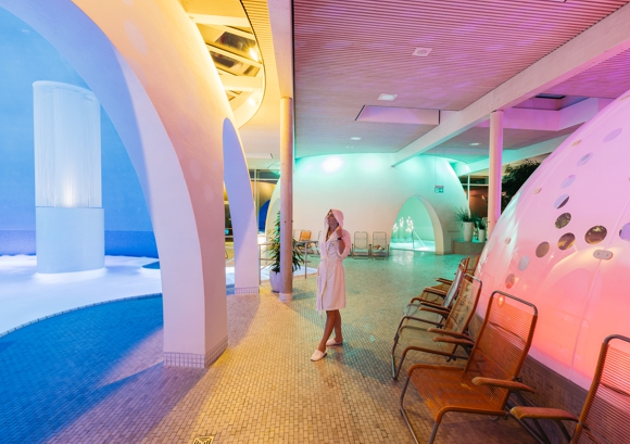 Therme Bad Aibling, Frau im Bademantel blickt auf Thermalbäder unter Kuppeln.