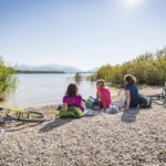 Drei Urlauberinnen machen Pause bei einer Radtour am See