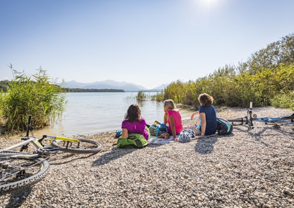Drei Urlauberinnen machen Pause bei einer Radtour am See
